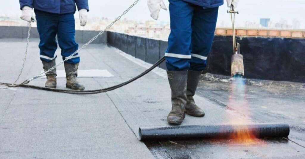 Trabalhadores fazendo obra de impermeabilização na laje do edifício