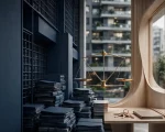 um grande edifício residencial contemporâneo, visto parcialmente em perspectiva, representando a complexidade da gestão condominial. Em primeiro plano, uma passagem ou estrutura arquitetônica dividida entre dois elementos: de um lado, linhas geométricas rígidas, grades, documentos, carimbos e elementos burocráticos simbolizando excesso de regulamentação; do outro, uma estrutura mais aberta e orgânica, representando experiência profissional, diálogo, mediação, gestão e capacidade prática. No centro da composição, sugerir visualmente uma balança em equilíbrio ou uma ponte conectando esses dois mundos, transmitindo a ideia de que a regulamentação deve organizar e proteger sem criar barreiras desnecessárias à entrada e à permanência de profissionais qualificados.