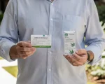 Um morador em uma área comum de um condomínio segurando uma embalagem de medicamento a base de cannabis